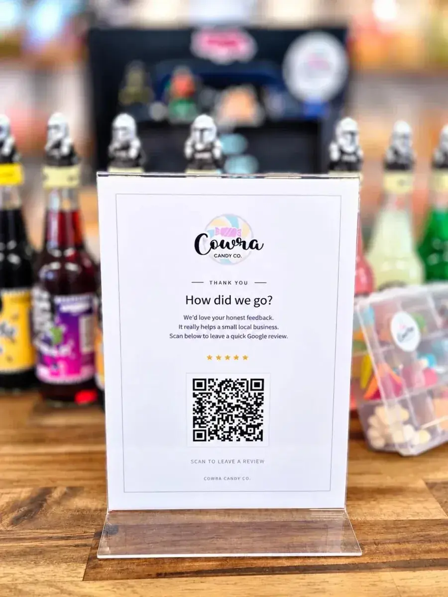 A Google review stand on the counter at Cowra Candy Co, reading "How did we go?" above a QR code